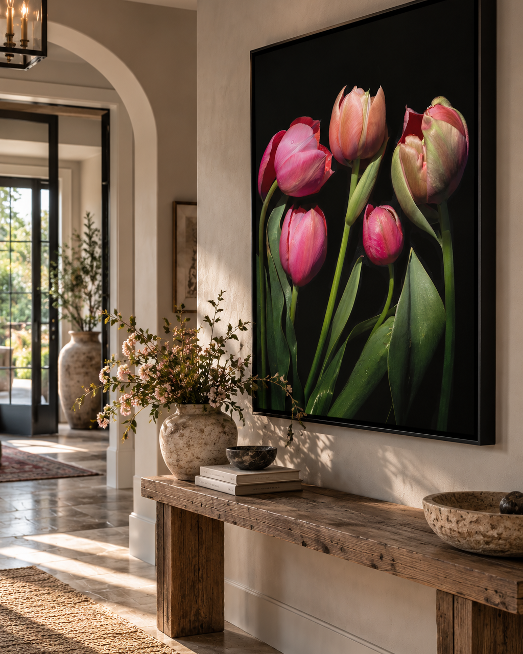 A large framed wall art print - A Fine Romance - featuring pink tulips on a black background, displayed in a styled interior hallway above a rustic wooden bench.