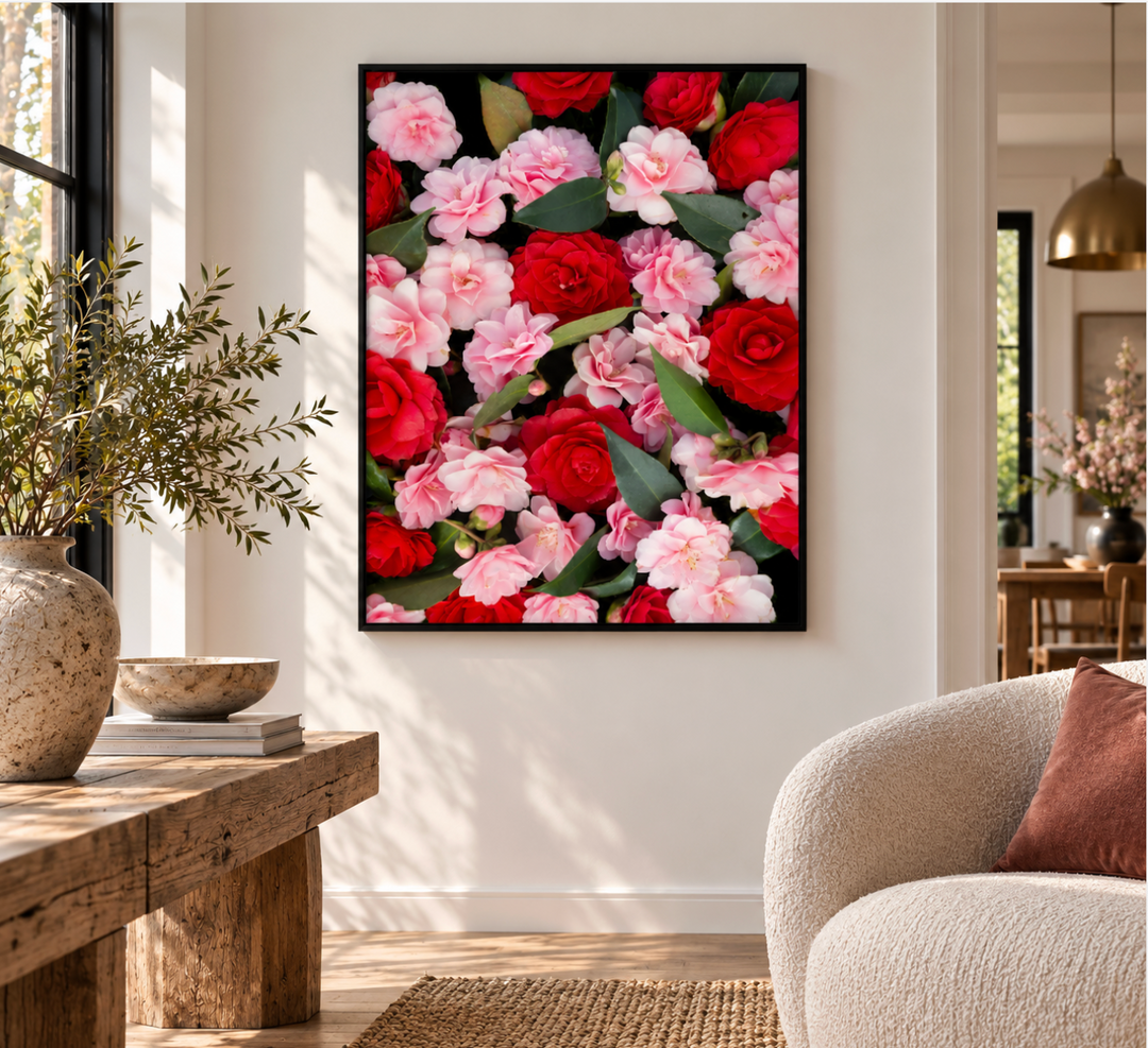 Front view of a red and pink camellia print filling a slim black frame on a cream living room wall.